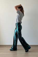 Cargar imagen en el visor de la galería, Mujer caminando con pantalón verde metalizado tiro alto de calce ancho mostrando caída fluida