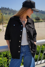Cargar imagen en el visor de la galería, Mujer usando chaqueta jeans negra estilo oversize, combinada con polera blanca y jeans azules, look urbano casual Fran del Solar