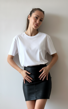 Cargar imagen en el visor de la galería, Modelo usando falda corta de cuerina croco negra tiro alto