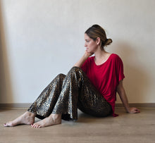 Cargar imagen en el visor de la galería, Mujer sentada usando pantalón dorado animal print, estilo casua